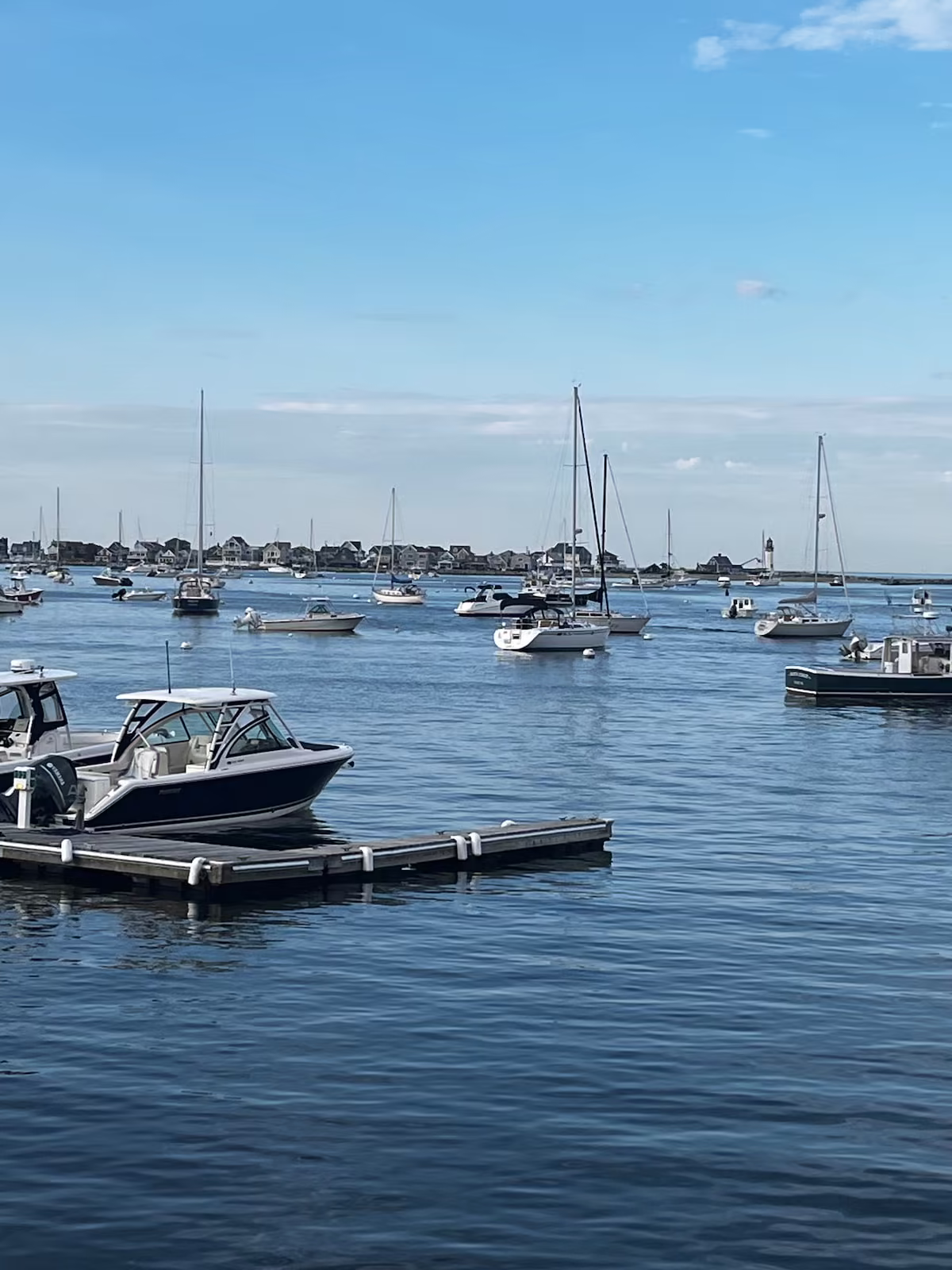 Sailboats on their moorings in Scituate Harbor, the lighthouse in the distance
