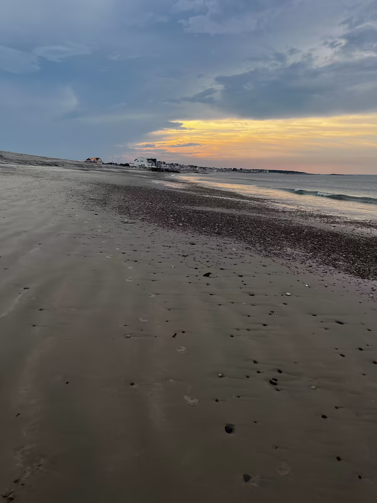 Pebble beach at low tide under a golden sunset band