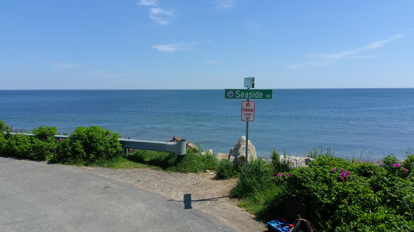 Drone view down Seaside Road toward the ocean: the street sign, the rocks, then open water